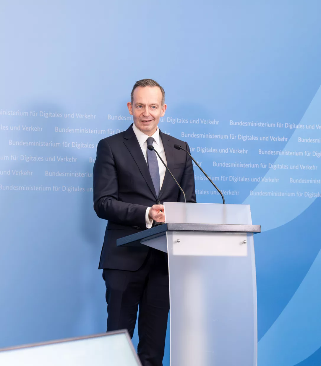 Volker Wissing, Bundesminister für Digitales und Verkehr, steht an einem Rednerpult vor einer blauen Wand.